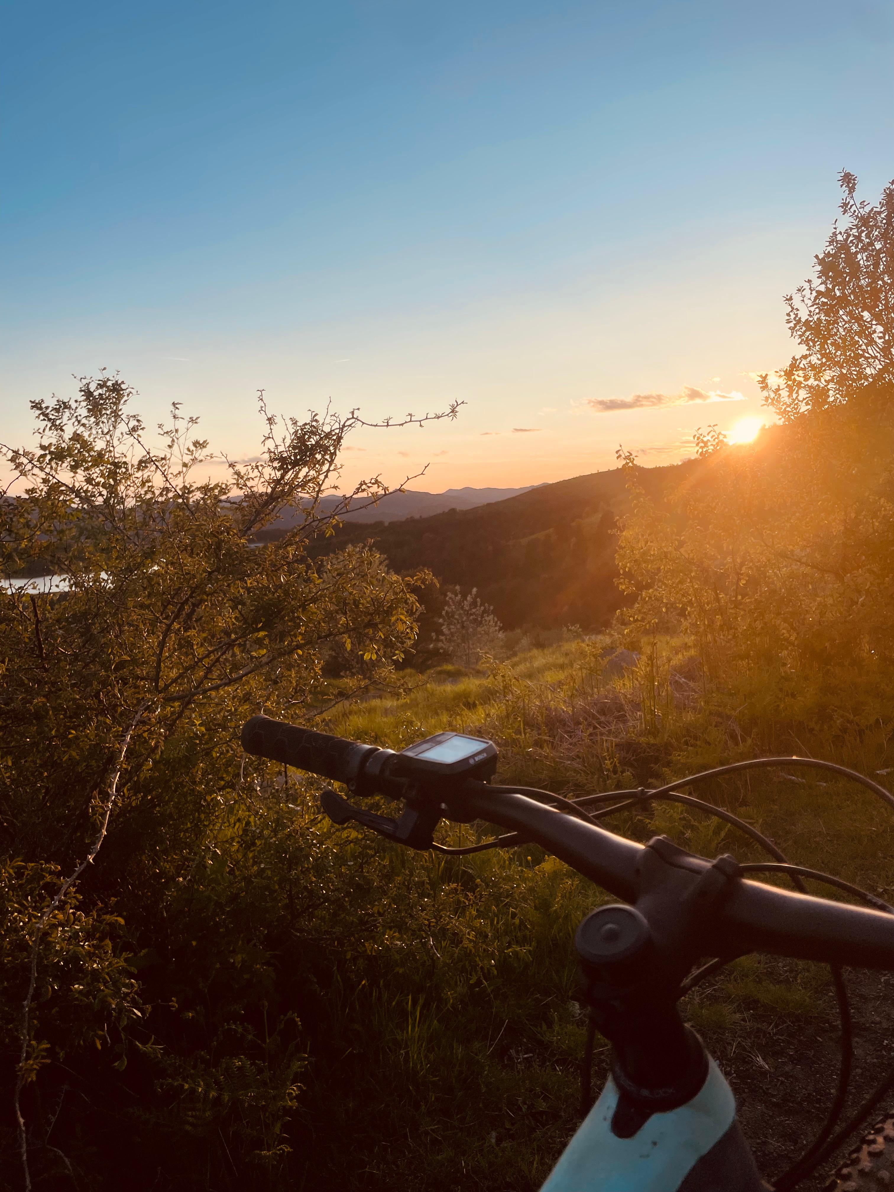 View of sunset over the mountain with a mountain bike's handlebars in front